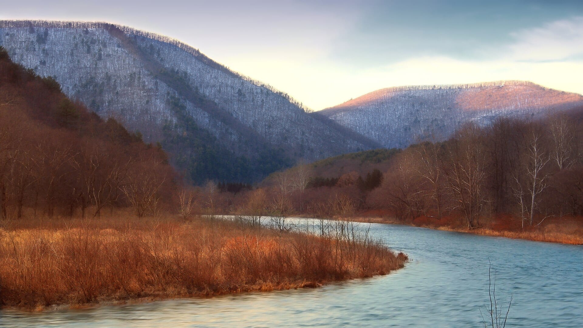 A clear river winding through a forested mountain valley